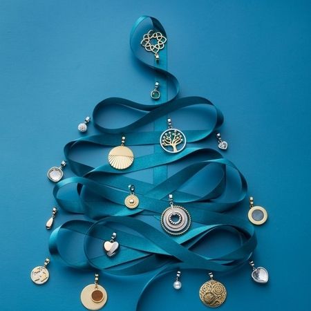 Festlicher Baumschmuck aus Schmuckanhängern und goldenen Medaillons mit Seidenband