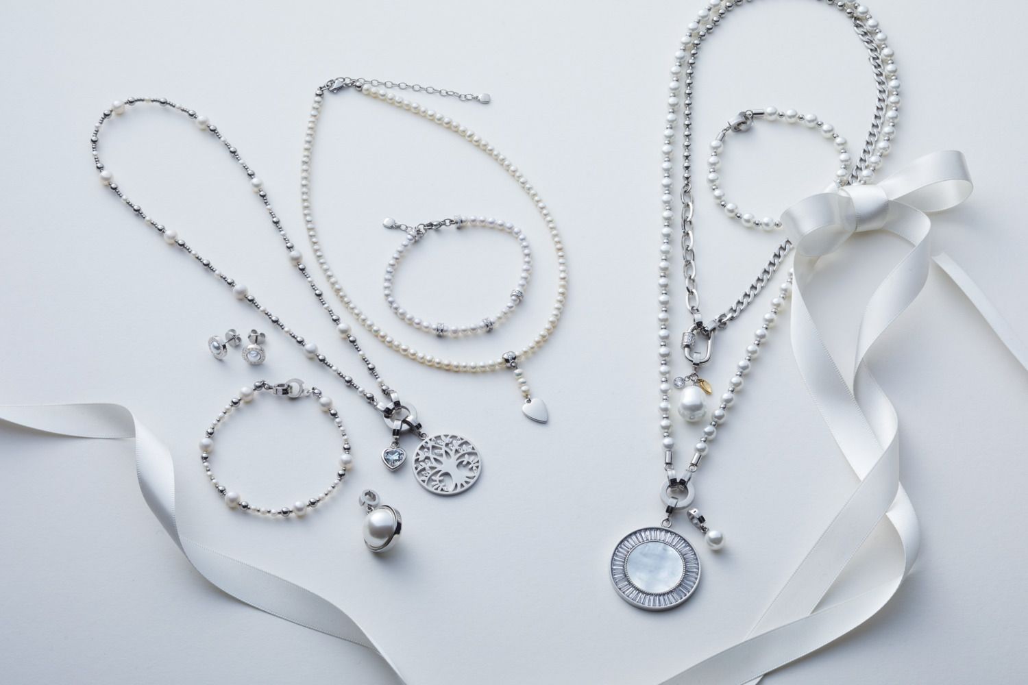 Eleganter Silberschmuck mit Ketten, Armbändern und Perlen auf weißem Hintergrund